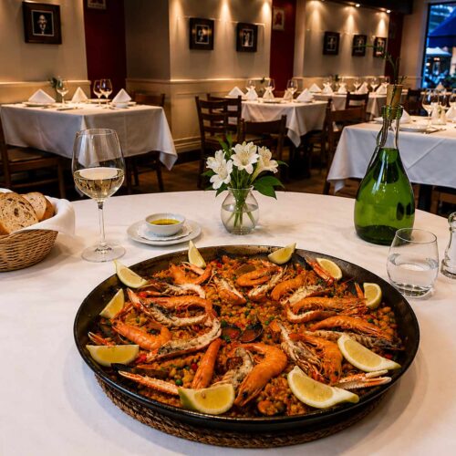 Grande paella de fruits de mer préparée au restaurant espagnol El Faro à Genève avec crevettes, langoustines, moules et citron frais.