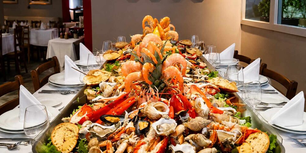 Vue spectaculaire d'un immense plateau ou banc de fruits de mer géant garni de crustacés, crabes, crevettes et coquillages, servi au restaurant El Faro dans le quartier des Pâquis à Genève