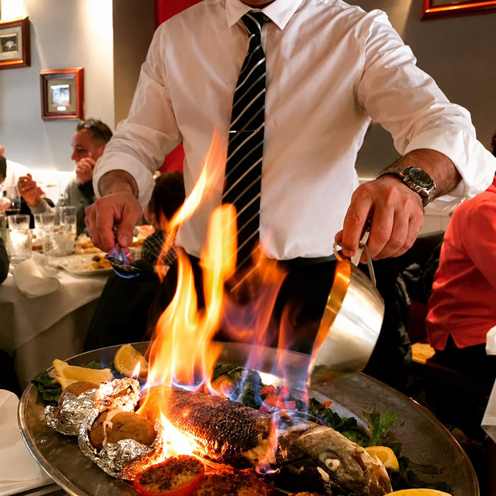 Un serveur du restaurant El Faro aux Pâquis à Genève procède au flambage spectaculaire d'un bar entier en croûte de sel sur un plat de service.