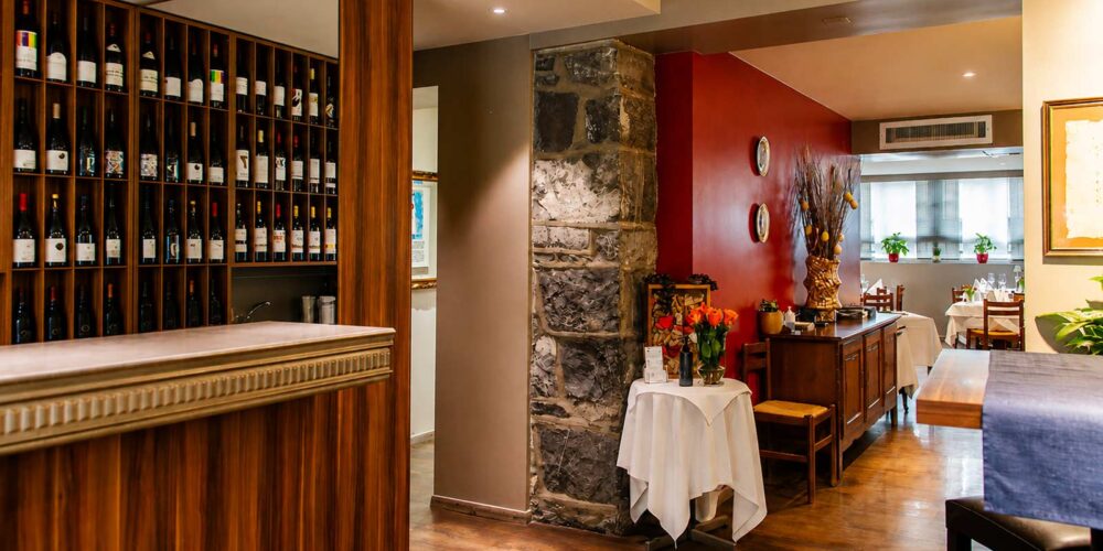 Vue sur le comptoir en bois, le présentoir à vins et l'aménagement intérieur du restaurant El Faro dans le quartier des Pâquis à Genève