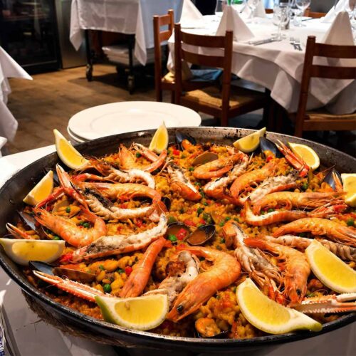 Grande poêle de paella traditionnelle aux fruits de mer et langoustines, servie au restaurant El Faro dans le quartier des Pâquis à Genève